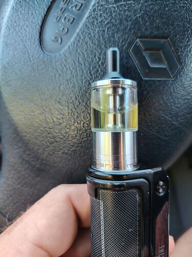 Une main tenant une cigarette électronique devant le volant d'une voiture sur lequel le logo Renault est visible. (Légendé par IA)