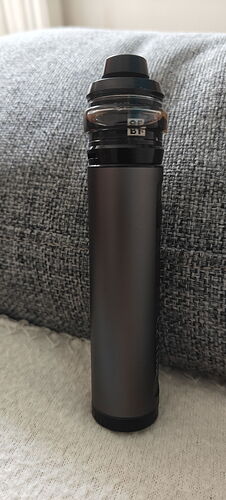 A black colored electronic cigarette or vape device is placed in front of a grayish-blue background. (Labeled by AI)