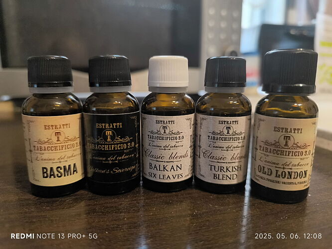 The five bottles of essence contain different flavors such as Basma, Balkan, Turkish Blend, and Old London, placed on a table. (Subtitled with AI)