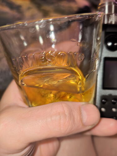 A hand holds a glass of Jameson, filled with a golden-brown liquid. (Caption by AI)