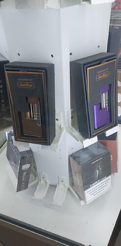 L'image montre un présentoir de cigarettes ou d'appareils de vapotage, avec des boîtes de différents produits exposées. (Légendé par IA)