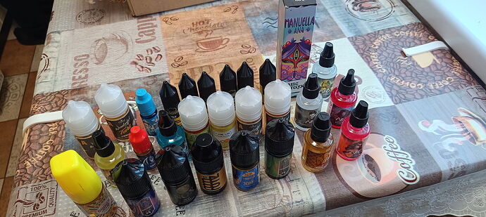 Various e-liquid bottles and vials in different colors and sizes are on the table, likely for use with electronic cigarettes. (Caption by AI)