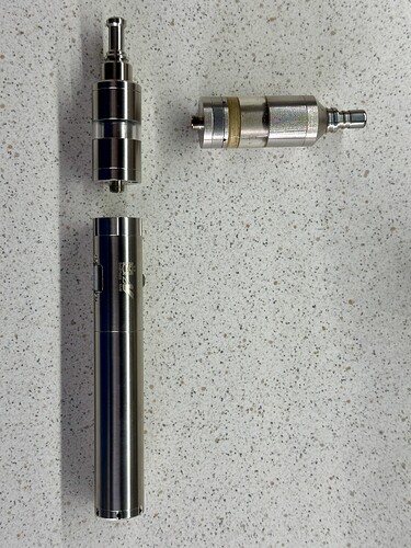 Az image egy elválasztott e-cigarettát ábrázol, amely tartalmaz egy fém testet és két különálló részt. (Feliratozva AI-val)