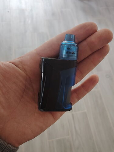 Un mod de vaporizer bleu et noir tenu dans une main. (Légendé par IA)