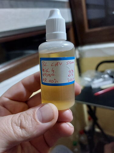 The image shows a bottle held in hand, containing yellowish liquid, and the label reads "B2 CAN 50ml MK 4 50/50 03 AR 10% 10g". (Labeled by AI)