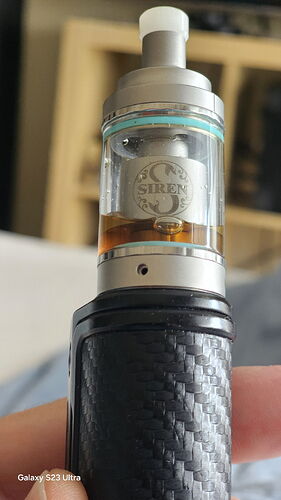 The image shows a Siren brand e-cigarette tank attached to a black, woven patterned grip. (Captioned by AI)