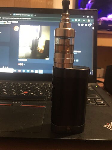 A képen egy fekete e-cigaretta van egy nyitott laptop billentyűzete előtt. (Feliratozva AI-val)