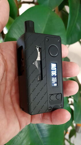 Tenue dans la main, une cigarette électronique ou un appareil de vapotage noirâtre est visible, avec un écran numérique et des boutons de commande. (Légendé par IA)