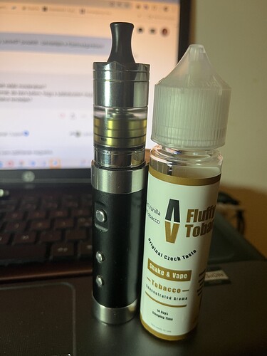 The image depicts a black e-cigarette and an e-liquid bottle, which are placed on a laptop keyboard. (AI-generated caption)