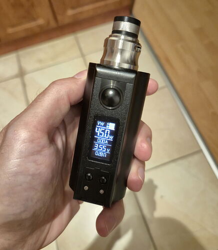 A hand holds a black electronic cigarette (vape) with a lit digital display. (Labeled by AI)