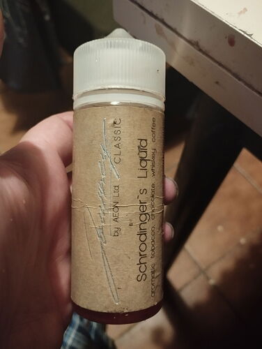 A hand holding a bottle labeled "Schrodinger's Liquid", and the label has brown paper. (Labeled by AI)