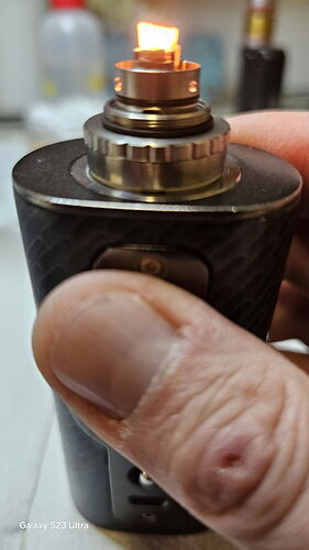 Une main tient une cigarette électronique fonctionnelle dont la flamme brûle. (Légendé par IA)