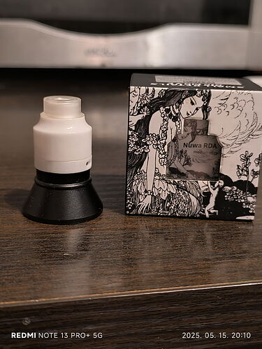 The image depicts a white-black cosmetic product and its gift box on the surface of a brown table. (Labeled by AI)