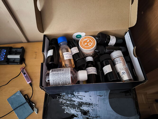 Une boîte ouverte est visible sur la photo, contenant diverses peintures liquides et en poudre, ainsi que des encres et des outils sur une table. (Légendé par IA)