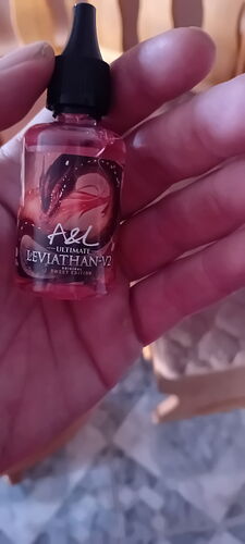 A hand holds a small bottle of A&L Ultimate Leviathan-V2 liquid. (Labeled by AI)