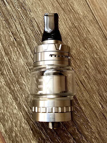 A vaper tank made of silver and clear glass is visible in the image. (Captioned by AI)