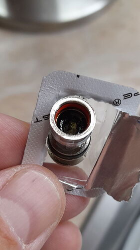 Egy kézben tartott, részben feltépett blister csomagolásban lévő fém vape cartridge kazetta látható. (Feliratozva AI-val)