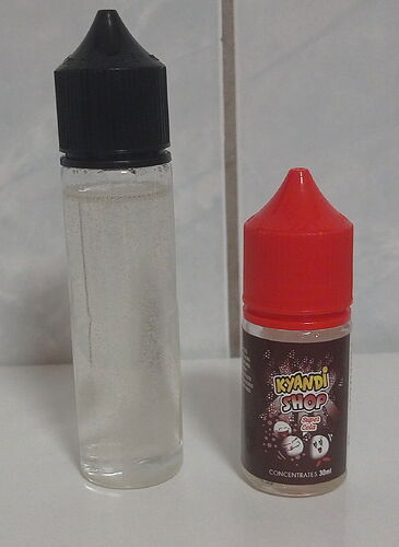 Két műanyag palack, az egyik átlátszó fekete kupakkal, a másik barna címkével és piros kupakkal, egy asztalon elhelyezve. (Feliratozva AI-val)