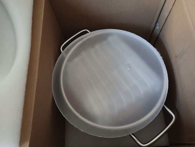 Une grande marmite ou casserole en métal avec un couvercle, stockée dans une boîte en carton. (Légendé par IA)