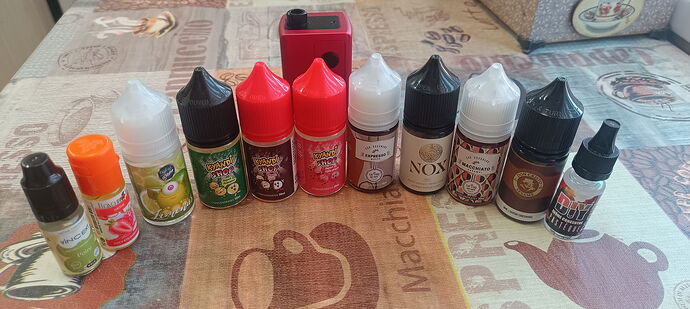 Divers flacons d'e-liquide et un appareil de cigarette électronique rouge sont visibles sur une table à motifs. (Légendé par IA)