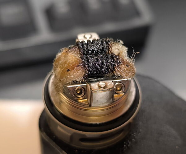 This image is a close-up photo of a worn-out and burnt coil used in a vape device. (Labeled by AI)