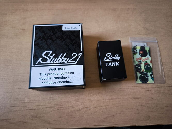 The image shows a product labeled "Stubby21" containing nicotine, next to a "Stubby TANK" box and a small pouch that likely contains something. (Autogenerated by AI)
