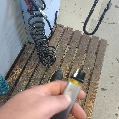 Une main tenant une poignée ou une poignée, avec un escalier en bois et un tuyau de ventilation enroulé visibles dans un environnement de chantier. (Légendé par l'IA)