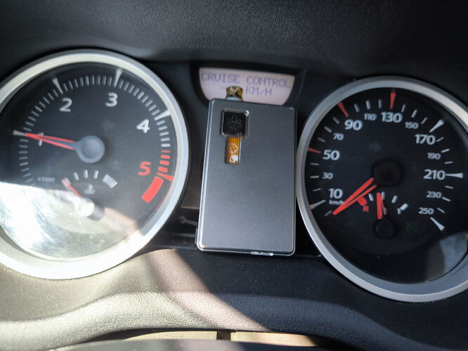 The image shows a car's dashboard, featuring the speedometer and tachometer, as well as a shiny, silver object. (Subtitled by AI)