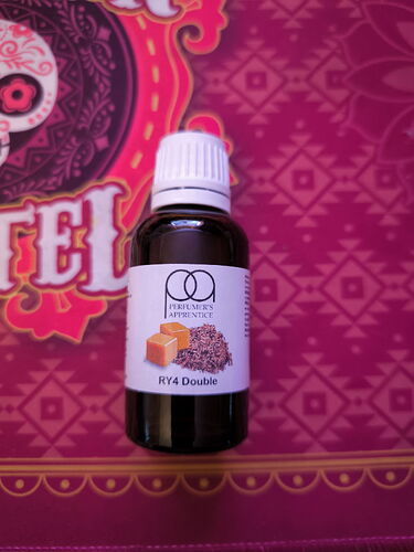 Az képen egy RY4 Double aromaolaj üveg látható egy díszes, mintás háttér előtt. (Feliratozva AI-val)