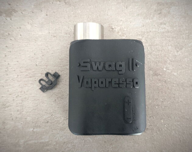 The image shows a Swag II Vaporesso vaping device, with a small black component next to it. (AI-generated caption)