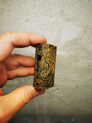 Une main tenant un petit objet en bois sculpté avec plusieurs ouvertures. (Légendé par IA)