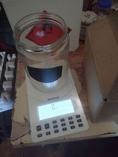 Egy üveg befőttesüveg áll egy digitális mérlegen, amely nulla értéket mutat. (Feliratozva AI-val)