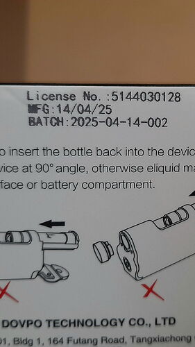 La photo montre un détail d'information produit et manuel d'utilisation, comprenant la date de fabrication (14/04/25), le numéro de lot de production (2025-04-14-002) et la bonne façon d'insérer un flacon de liquide dans l'appareil à un angle de 90°. (Légendé par IA)