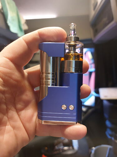 Une cigarette électronique bleue tenue dans une main, son réservoir visible. (Légendé par IA)