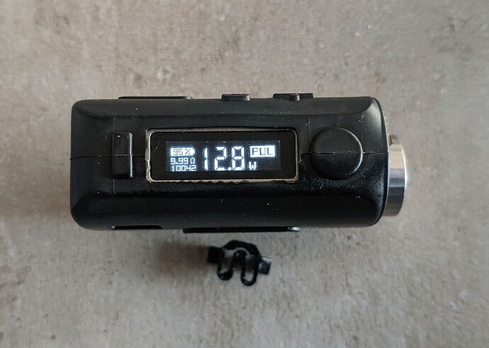 The image shows a black electronic device with "128 W" and "FULL" visible on its display. (AI-generated caption)