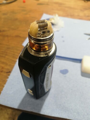 The image shows a vaper (e-cigarette) head on a workbench, surrounded by tools and accessories. (Caption by AI)