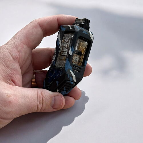 A képen egy kézben tartott, kamuflázs mintázatú vape eszköz látható. (Feliratozva AI-val)