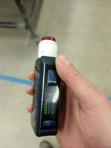 Un appareil tenu dans une main, doté d'un écran numérique et d'un capuchon rouge. (Sous-titré par l'IA)