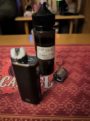 A vape device, a bottle of liquid, and a removable accessory are visible on the table. (Autocaptioned AI)
