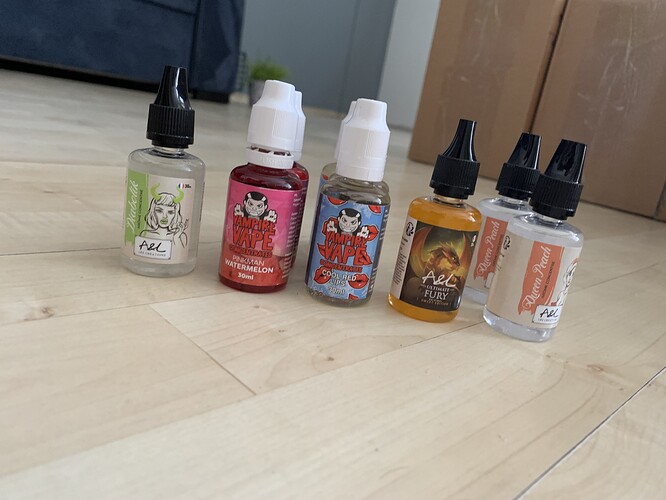 Five bottles containing different e-cigarette liquids are lined up on a wooden floor. (Caption by AI)