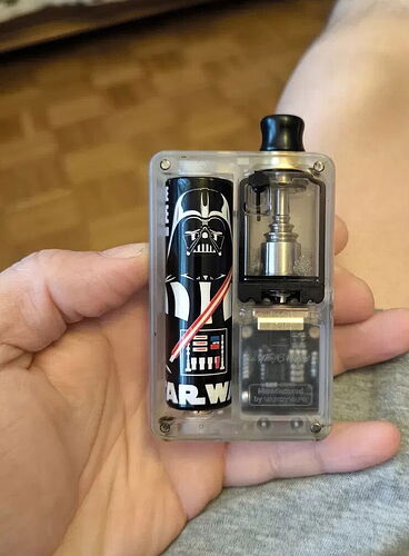 Egy kézben tartott, átlátszó tokú elektronikus cigaretta, amelynek akkumulátora Darth Vader mintával van díszítve. (Feliratozva AI-val)