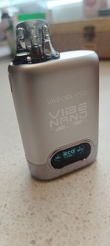 The image shows a silver Vaporesso Vibe Nano e-cigarette on a light, mottled surface. (Labeled by AI)