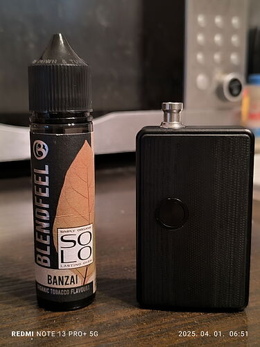 A képen egy BLACK POD vape készülék és egy Banzai ízesítésű BLENDFEEL e-liquid palack látható. (Feliratozva AI-val)