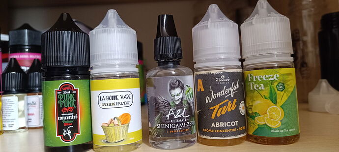 Az asztalon különböző e-liquid palackok sorakoznak, különféle márkákkal és ízekkel. (Feliratozva AI-val)