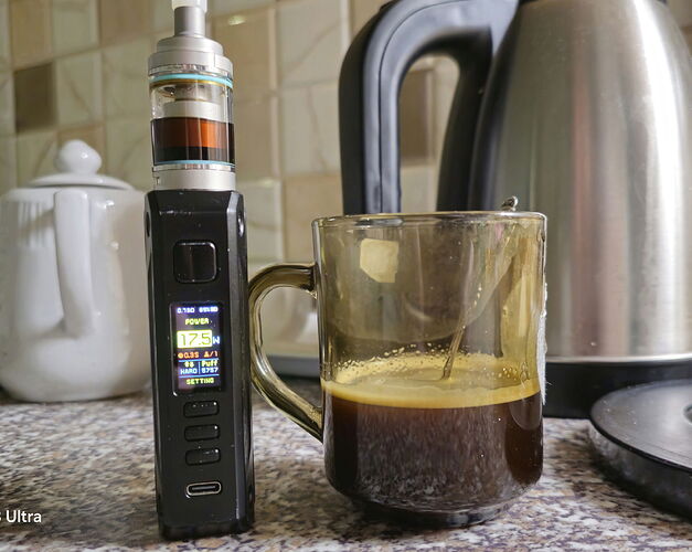 Une cigarette électronique se trouve à côté d'une tasse de café avec une bouilloire en arrière-plan. (Sous-titré par IA)