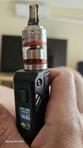 Une cigarette électronique à écran numérique tenue dans une main, dont le réservoir est rempli d'un liquide rouge. (Sous-titré par IA)