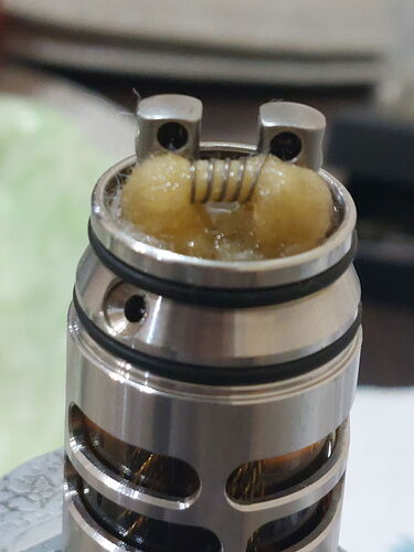 Cette image présente un coil de vape mécanique, avec le fil enroulé autour d'une bakélite ou d'un matériau isolant. (Légendé par l'IA)