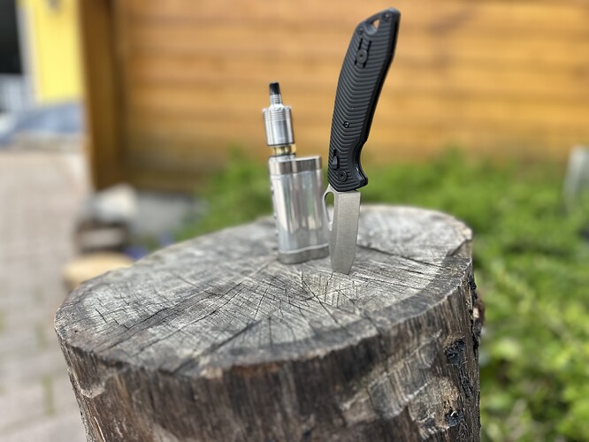 Sur la photo, un appareil de vapotage métallique est placé dans une bûche en bois, et un couteau noir est visible. (Légendé par IA)