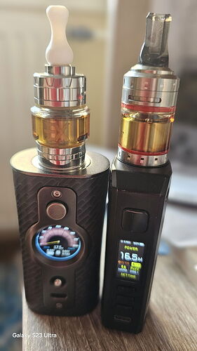 Két különböző elektronikusan szabályozott e-cigaretta mod, amelyek fém és üveg tankkal, folyadékkal töltve állnak egymás mellett. (Feliratozva AI-val)