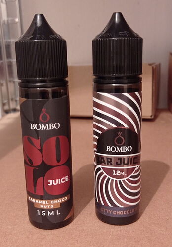 Two bottles of Bombo e-liquid of different flavors stand next to each other on a table with Hungarian labels. (Subtitled with AI)